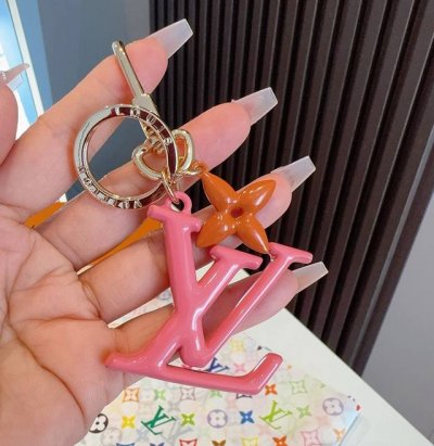 Lv钥匙扣珐琅工艺Lv字母挂件 Pop Flower包和钥匙扣的魅力非常适合为皮革配饰增添标志性的色彩，其特点是金色金属钩环，点缀着充满活力的Lv首字母和会标花
